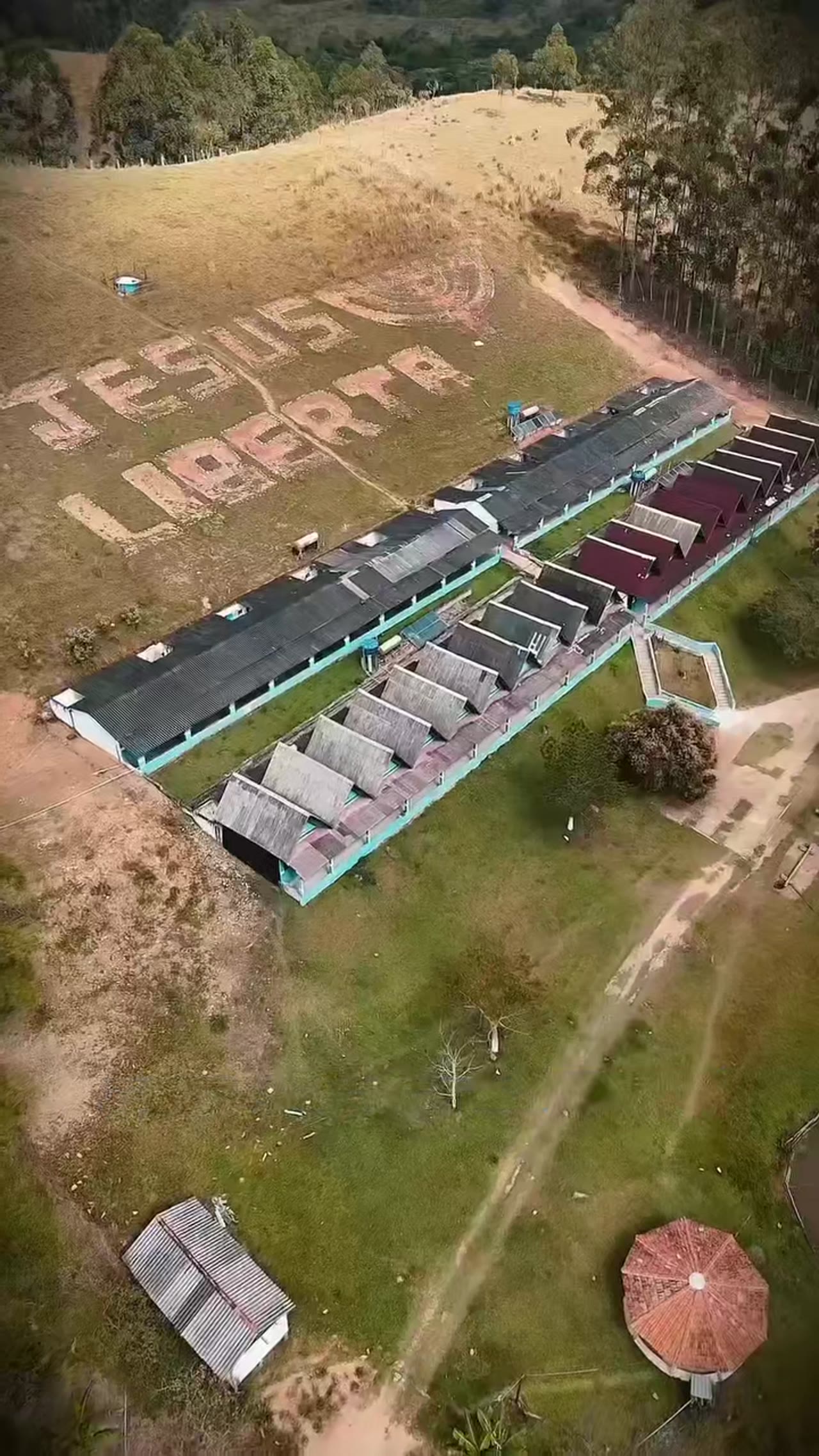 Vista aérea da Comunidade Há Uma Esperança Jesus, com a mensagem 'Jesus liberta' desenhada na encosta, em Caçapava/SP
